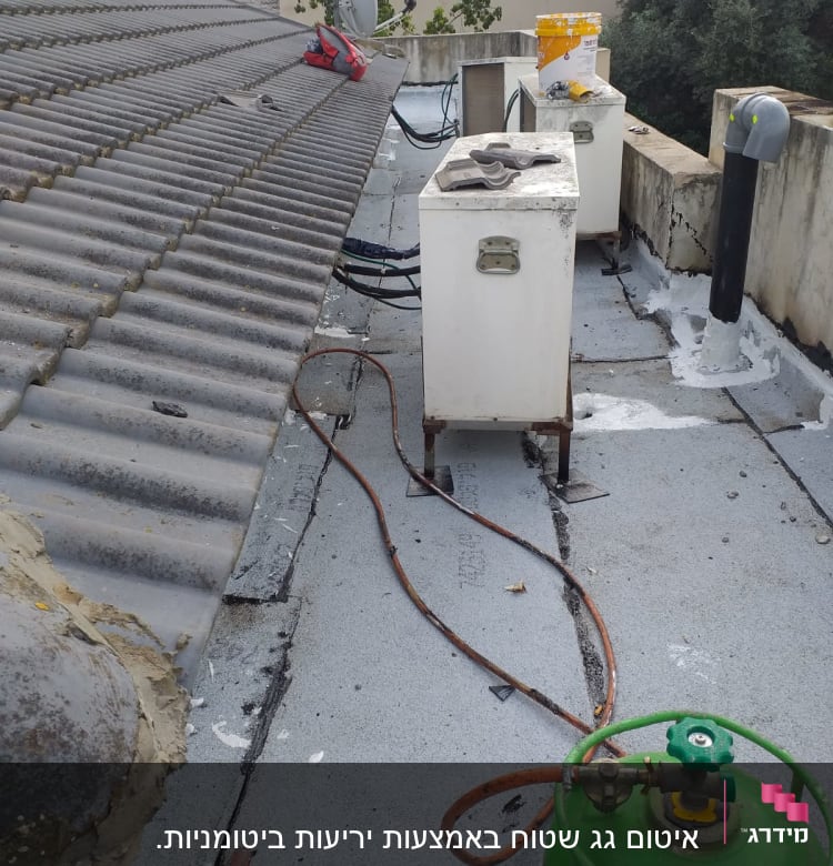 גג עם חומרי איטום, צינורות ומיכל גז ירוק